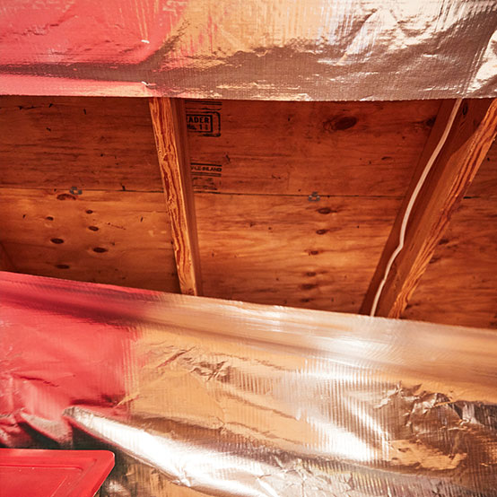 An attic with insulation and a radiant barrier partially installed