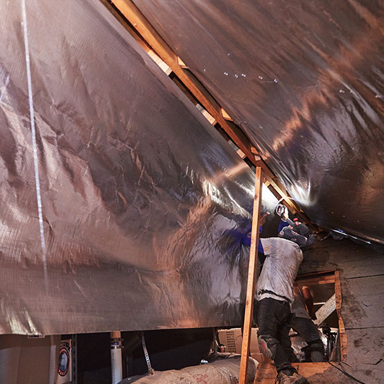 A HeatBusters technician install a radiant barrier in an Austin attic